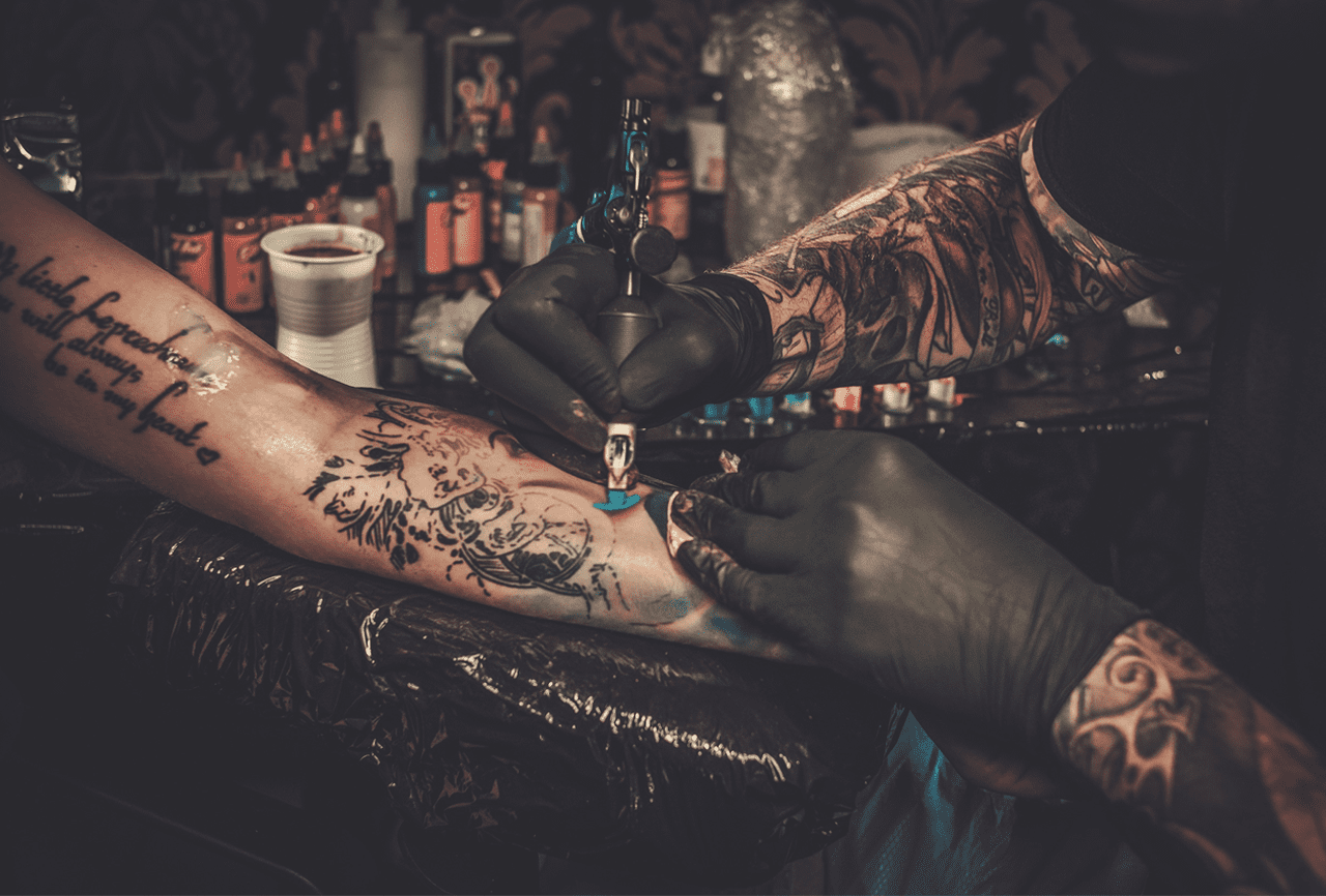tattoo artist create a tattoo on anthor guy hand