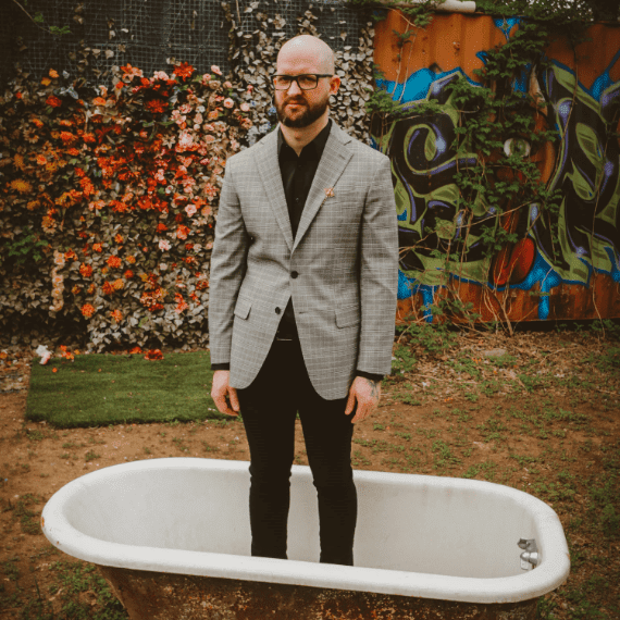 Mason Buchanan Wearing Coat Paint Stand In A Bathtub